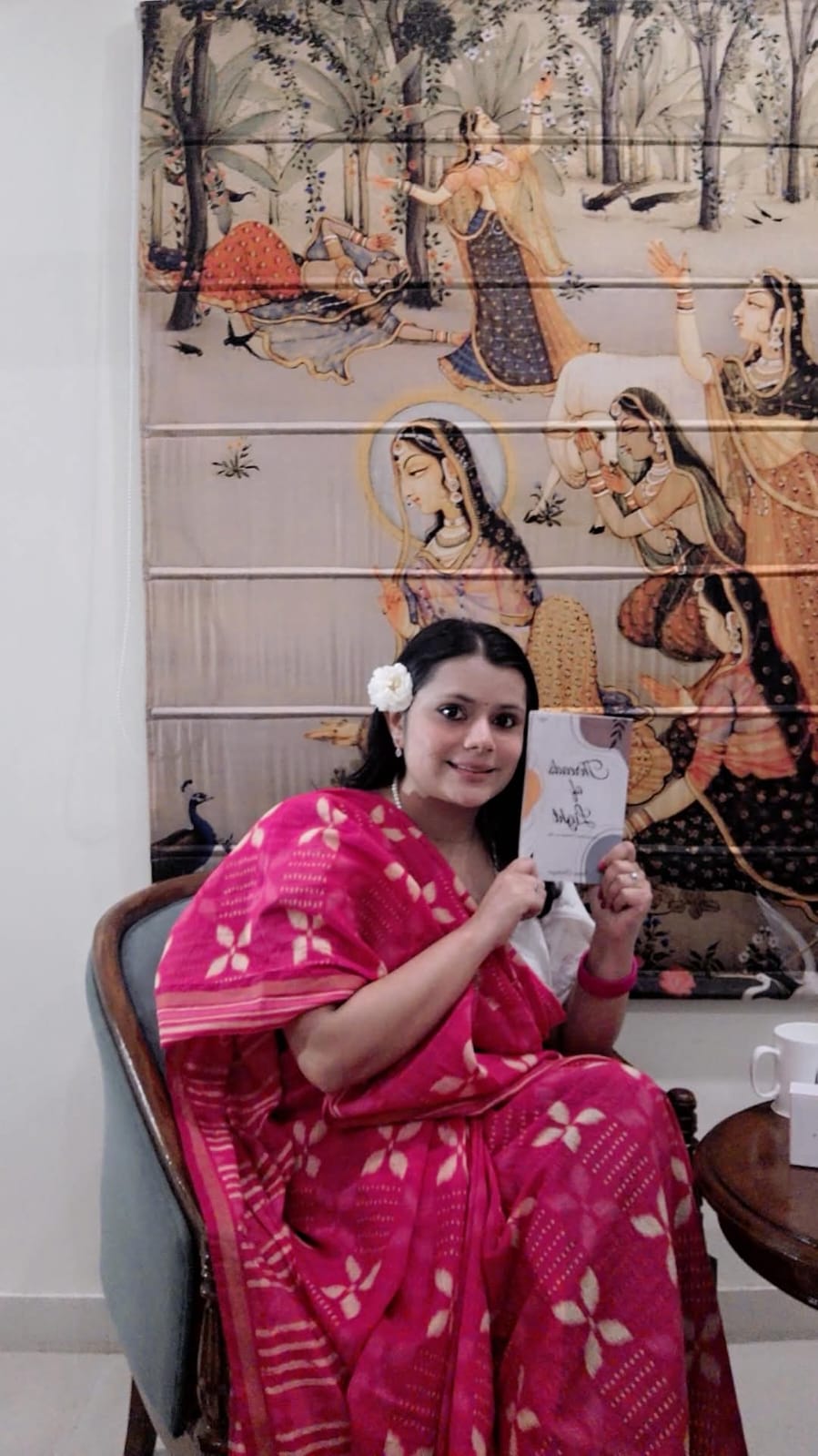 Shivani seated, holding her book Threads of Light